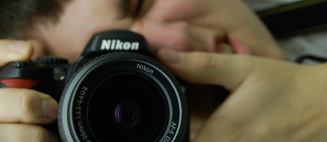 Robert looking through the viewfinder of a Nikon photo camera